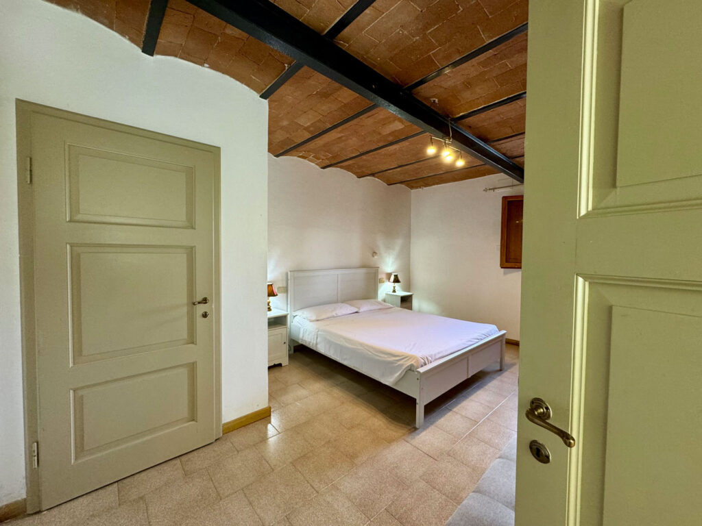 Camera da letto dell'agriturismo Tinti Chianti a Certaldo con letto matrimoniale e soffitto in cotto toscano