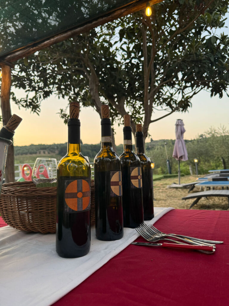 Bottiglie di vino Chianti adagiate sul tavolo sotto al gazebo in giardino al tramonto.